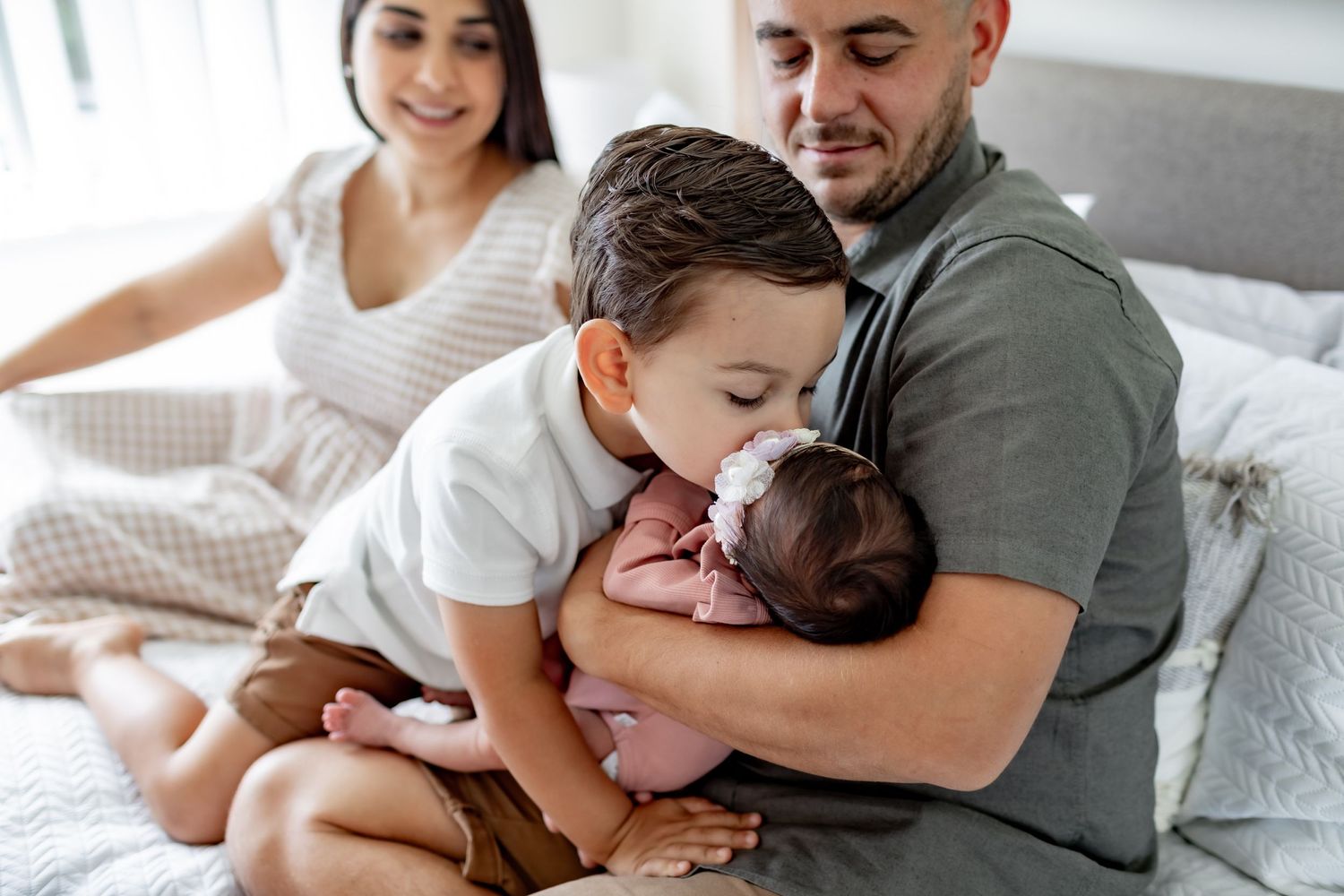 Tender family moment captured on bed with siblings bonding.