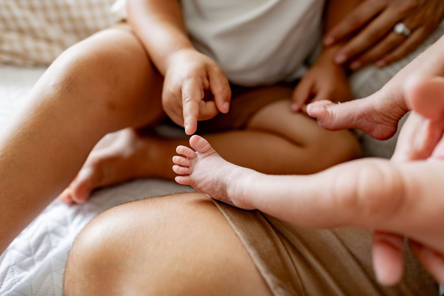 Close-up of tiny baby feet being held gently on textured fabric.