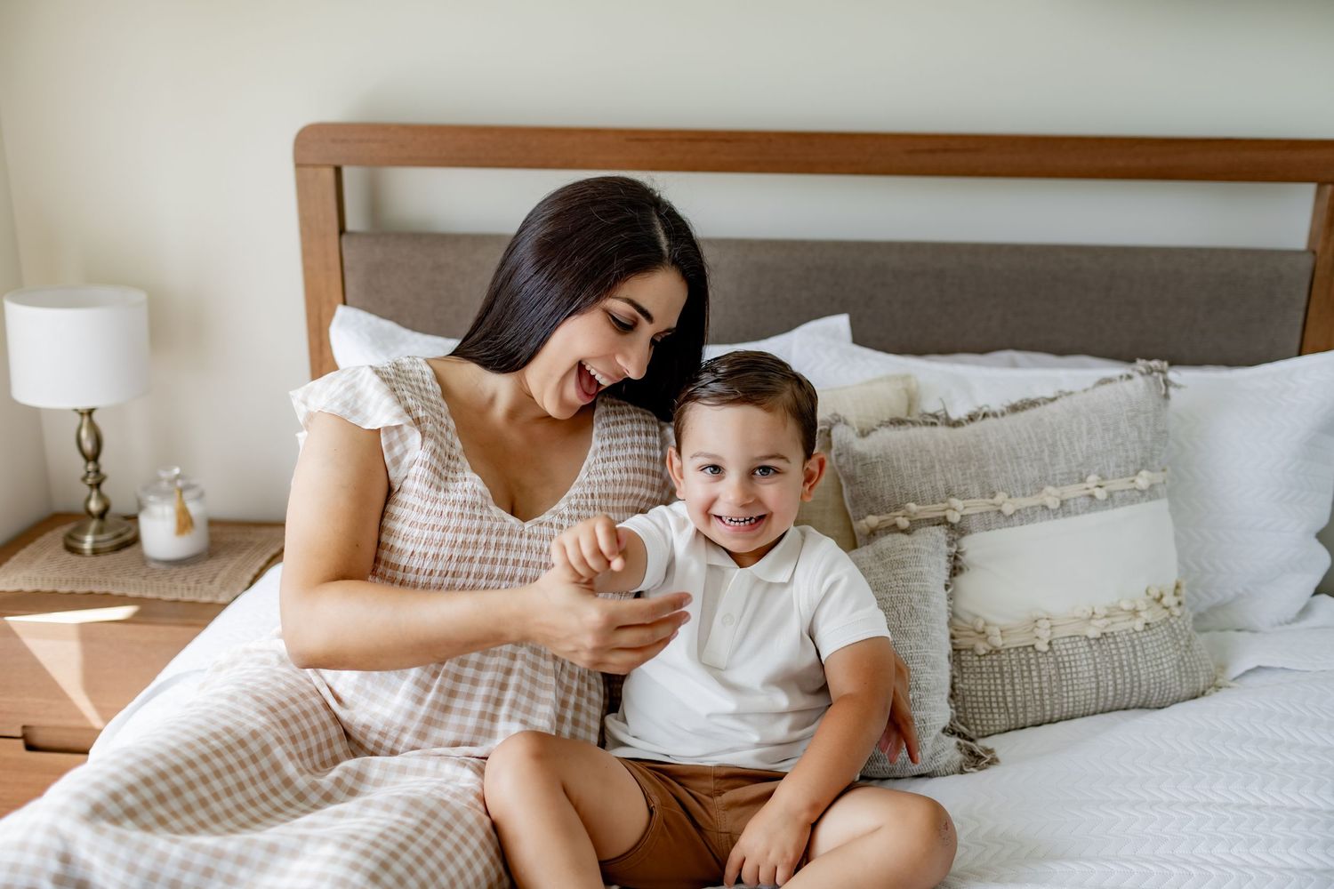 Intimate moment of parent and child sitting together on cozy bed with decorative pillows.