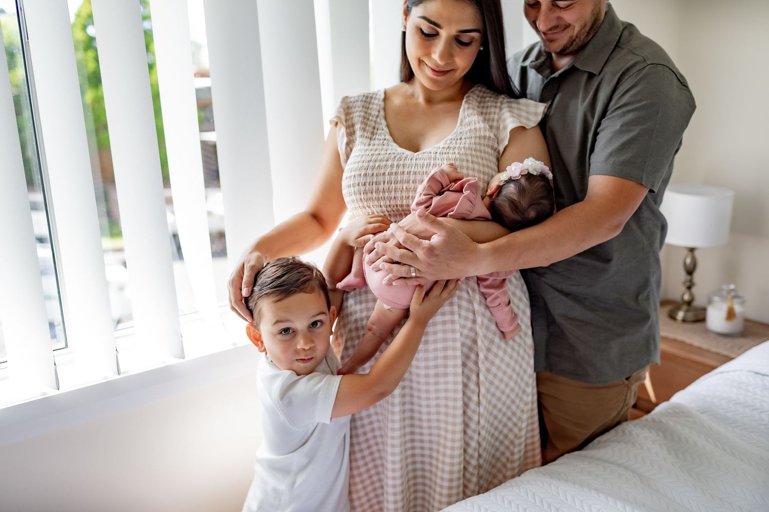 A family sharing a loving moment together with their newborn baby in a sunlit room.