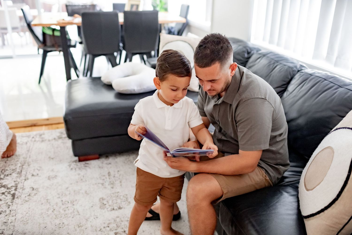 Child and adult viewing digital tablet together while standing in living room.