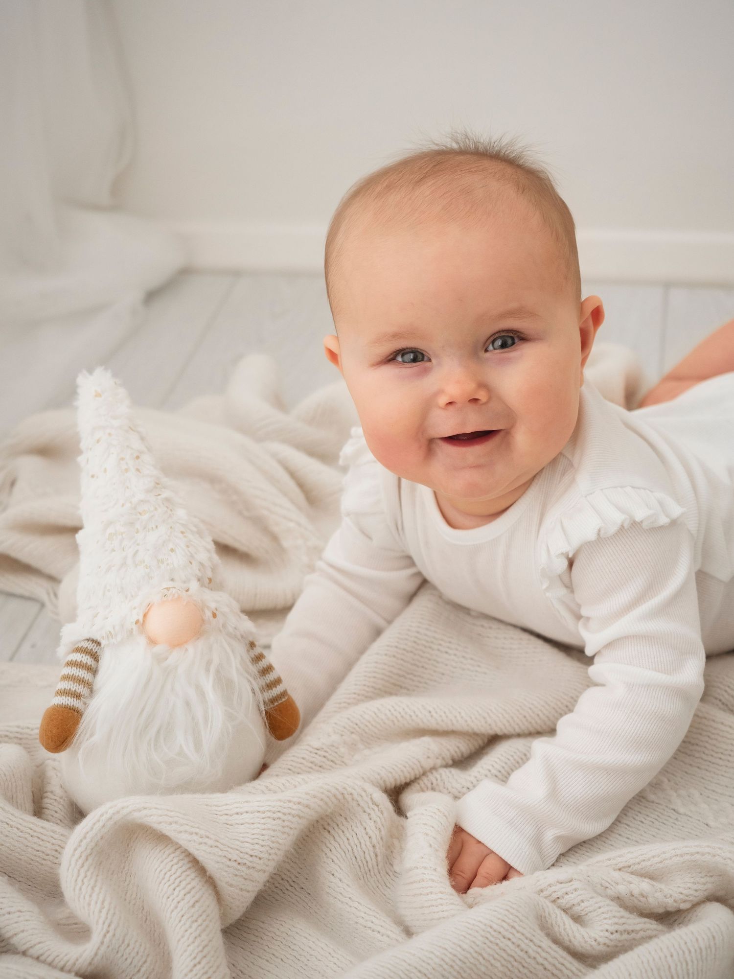 A close up portrait of a 7 month baby laying on a cream blanket during a photo shoot in Didcot, Oxfordshire