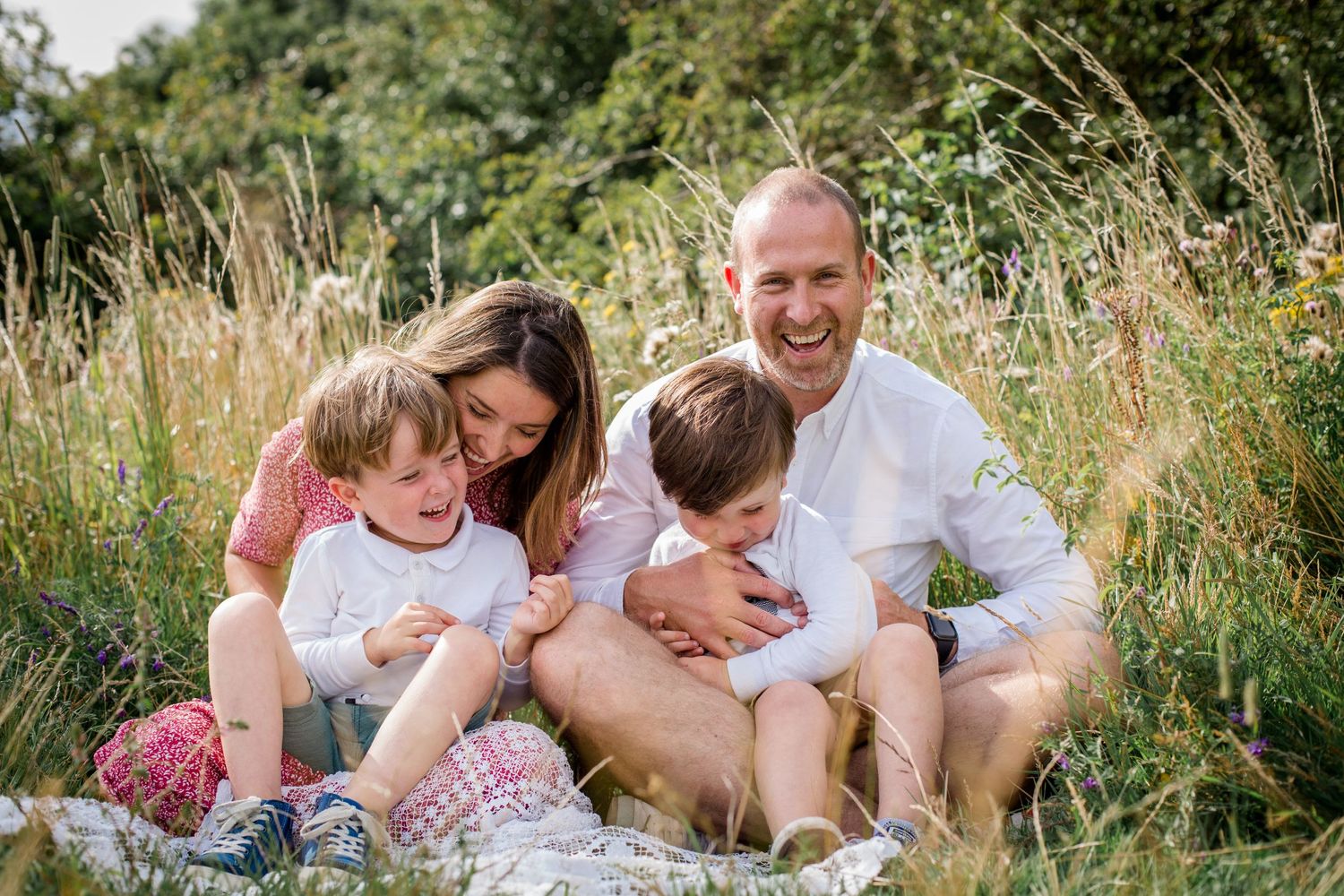family sitting in the grass on a summer day all laughing