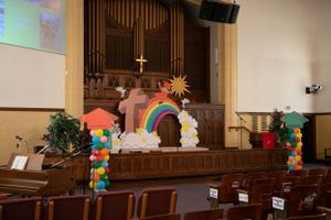 Church sanctuary interior with wooden pews and colorful decorations on stage.