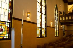 Row of stained glass windows in a church with warm interior lighting.