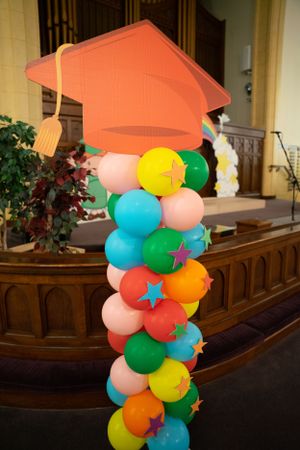 Colorful balloon arch display with pink, blue, yellow and green balloons in church setting.