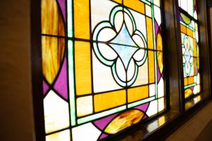 Close-up of decorative stained glass windows with yellow and pink geometric patterns.