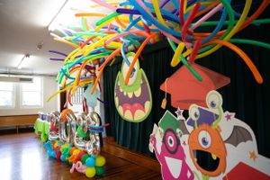 Vibrant monster-themed party decorations hang from the ceiling with colorful balloons and twisted streamers.