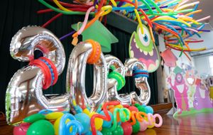 Colorful party decorations with balloon letters, streamers, and monster-themed cutouts line a hallway ceiling.