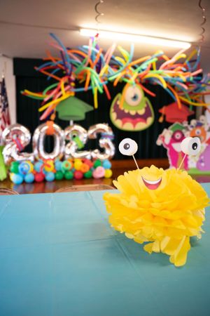 Yellow tissue paper decoration with googly eyes sits against turquoise backdrop at a monster-themed party.