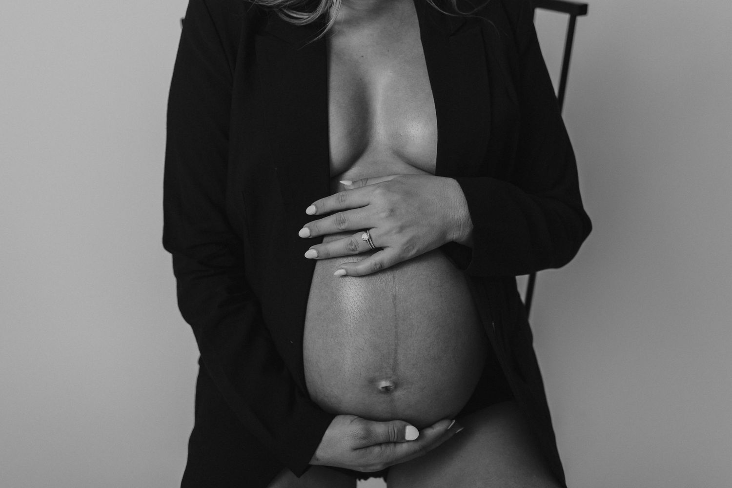 Artistic black and white pregnancy photo with hands tenderly holding bare baby bump.