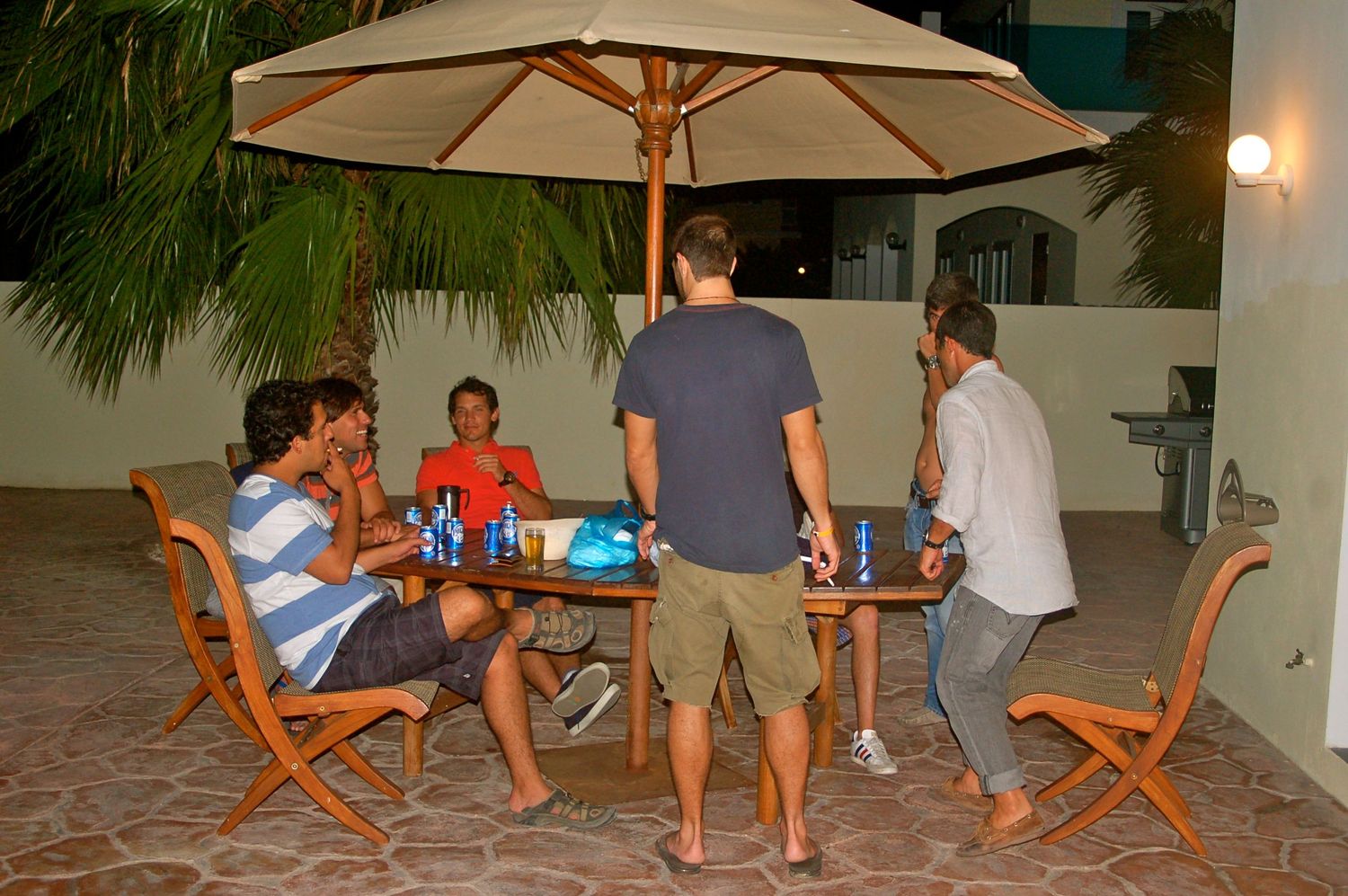 Group gathered for an outdoor dinner party under a patio umbrella.