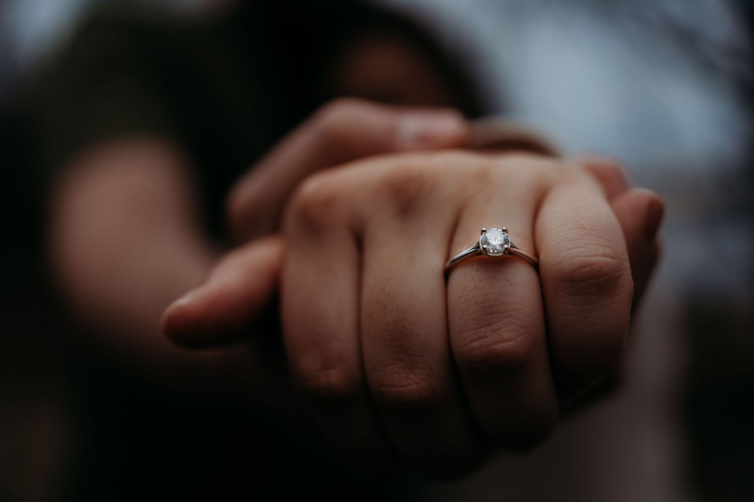 Close-up shot of hands with an engagement ring showing tender affection.