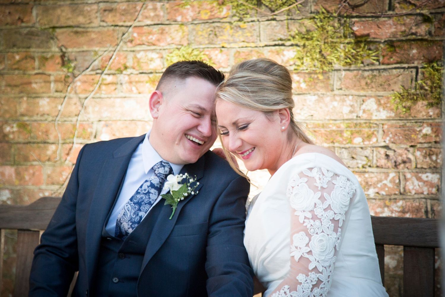 Happy bride and groom smiling on a bench