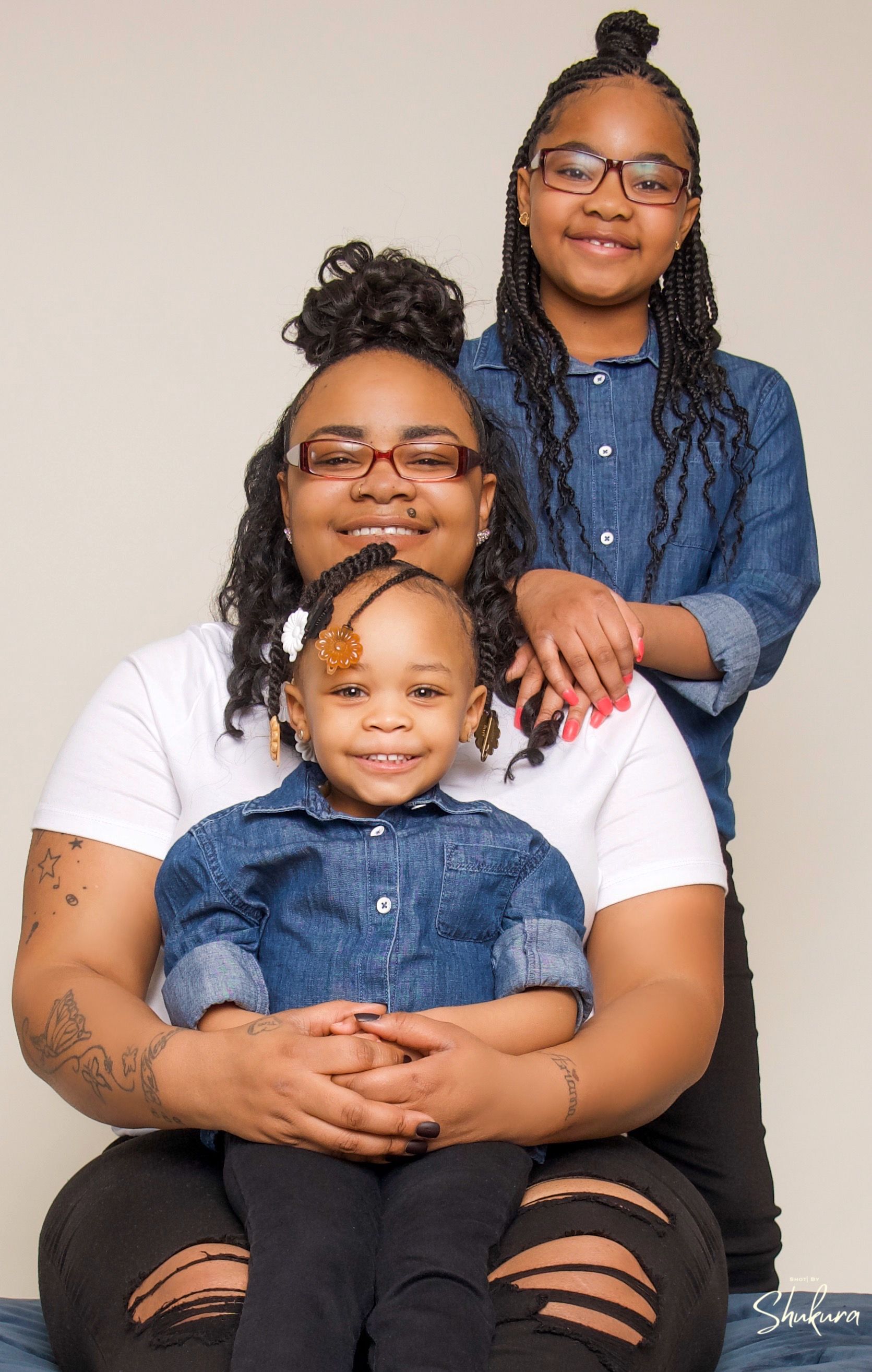 Three people in denim and white casual wear pose together for a family portrait.