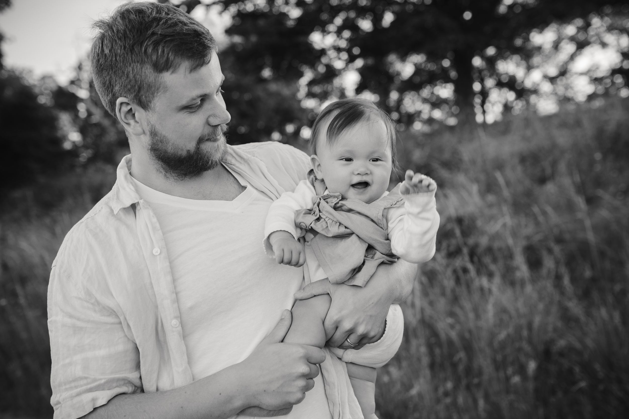 A tender moment between parent and baby outdoors in black and white.