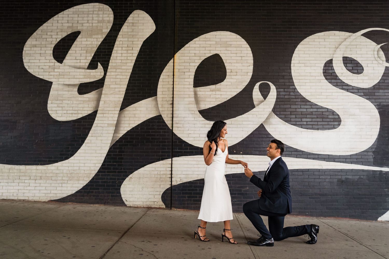 Proposal scene against urban wall art with 'Yes' text in dramatic black and white setting.