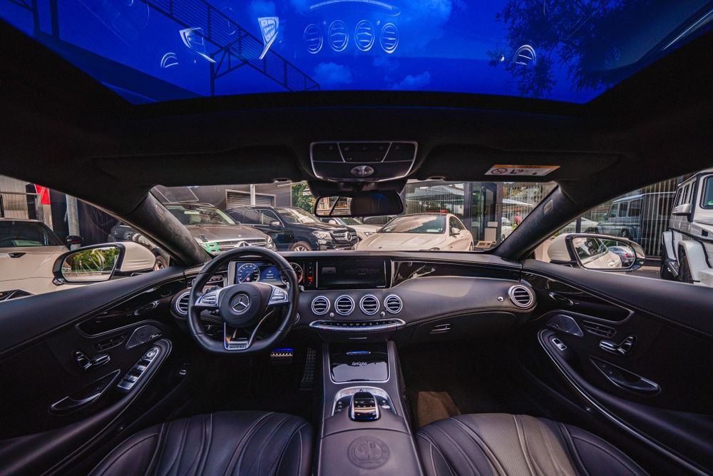 Luxurious Mercedes-Benz interior dashboard with blue ambient lighting and digital displays.