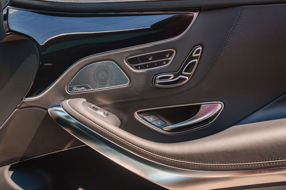 Luxurious Mercedes-Benz door panel controls with leather trim and metallic accents.