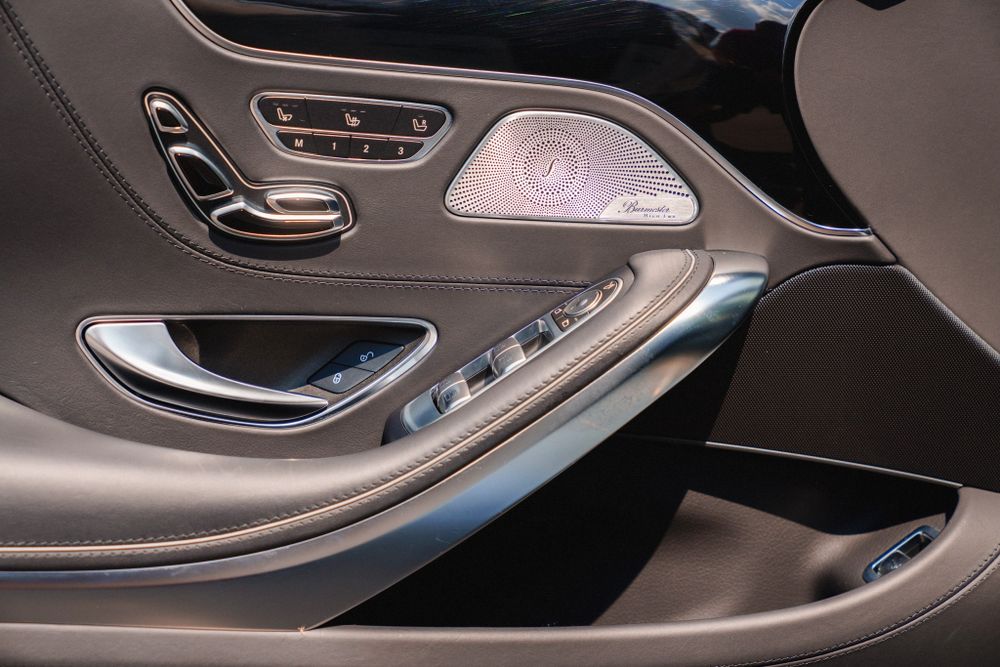 Close-up of Mercedes-Benz door panel controls with metallic accents.