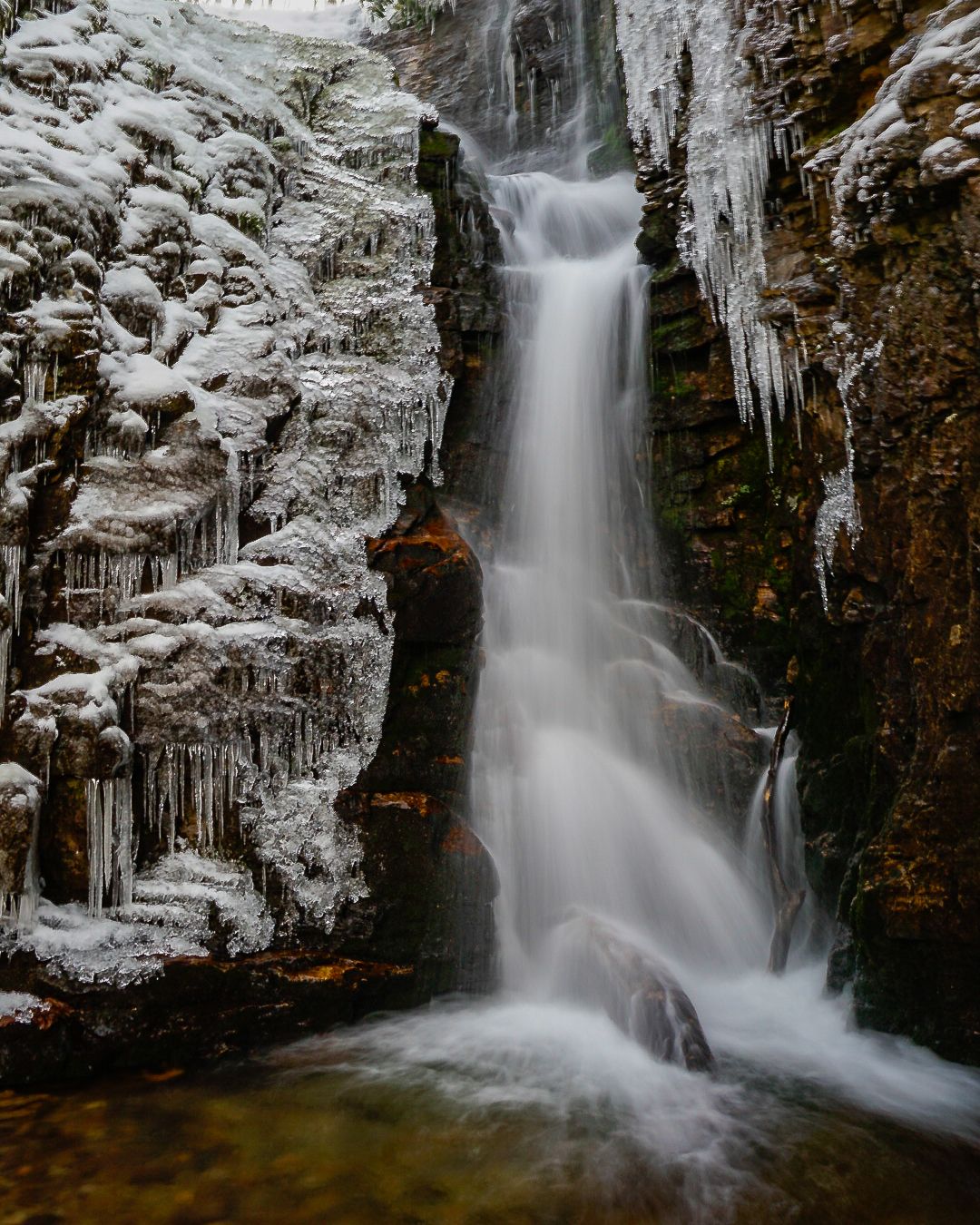 Snow covered rocks frame Rock Creek Falls in this long exposure photograph