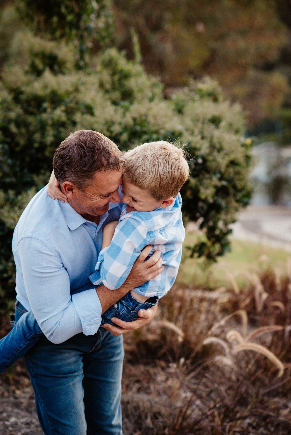 A tender moment captured between parent and child against a backdrop of ornamental grasses.