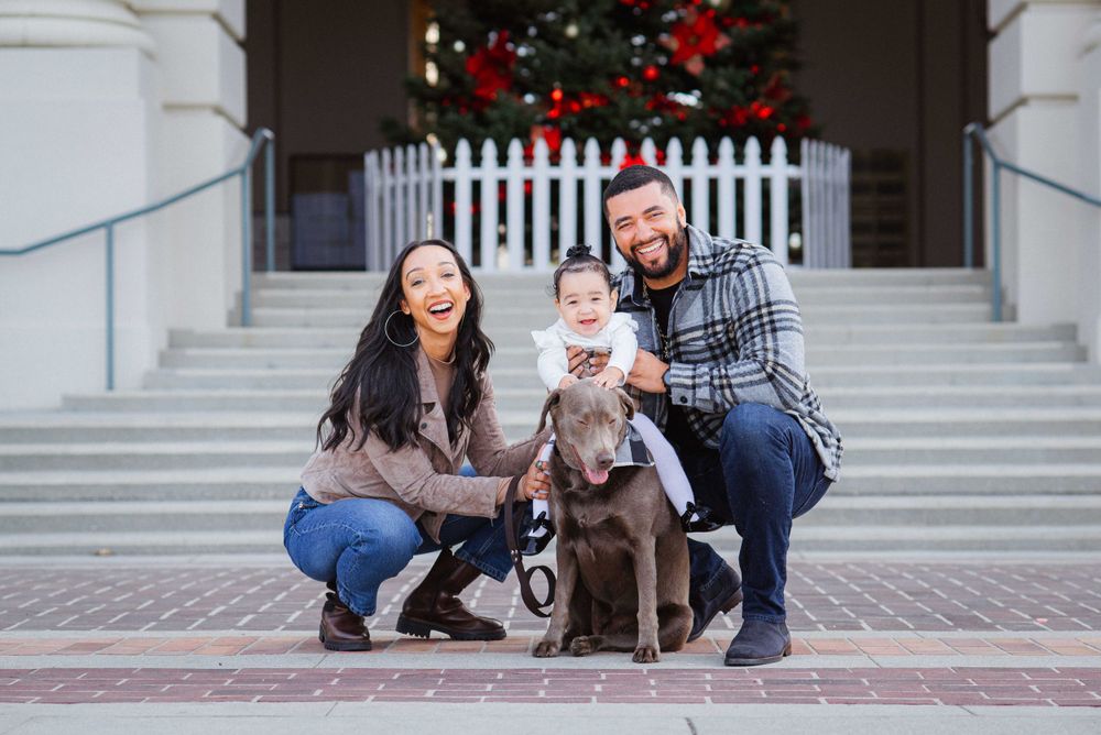 Holiday family portrait session with Christmas decorations and white picket fence in background.