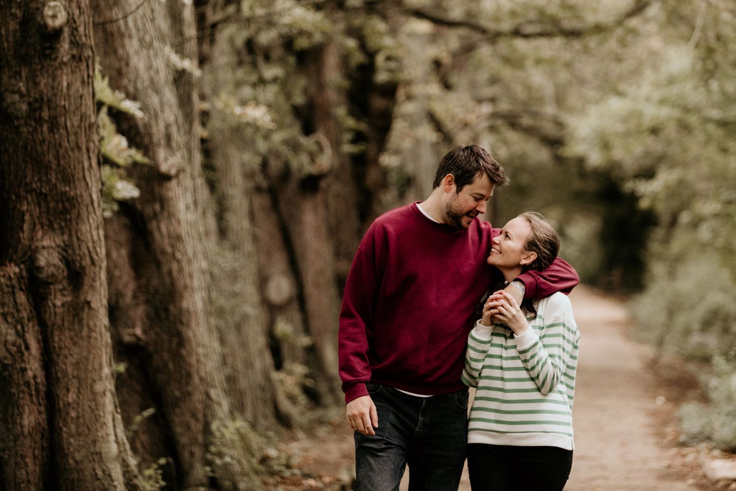couple arms around each other walking through woods