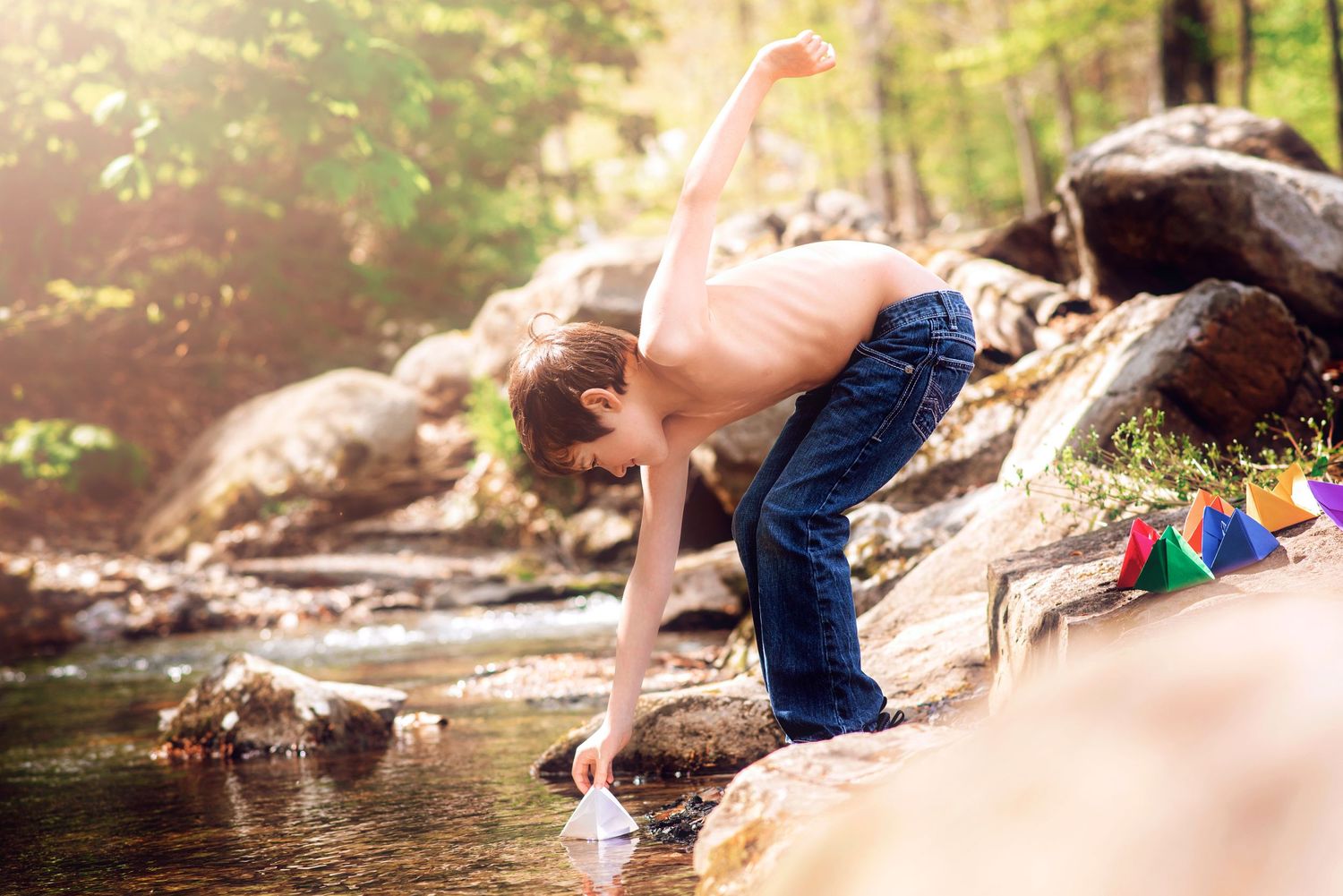 Child exploring creek bed on sunny summer day in forest.