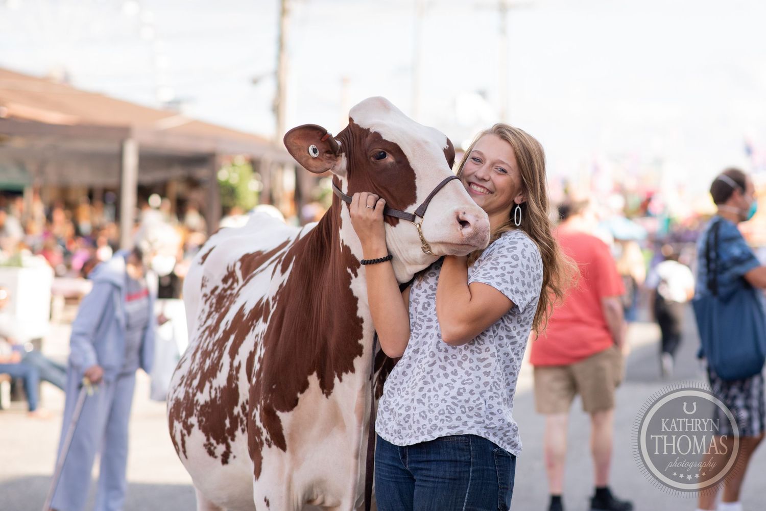 A young exhibitor shares a tender moment with their dairy cow at a county fair.