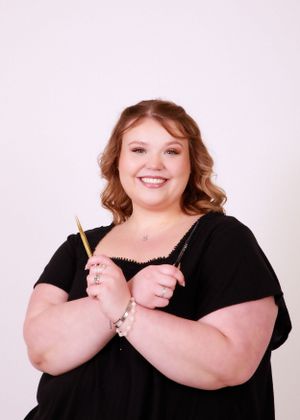 Woman in black top holding makeup brush with cheerful expression.