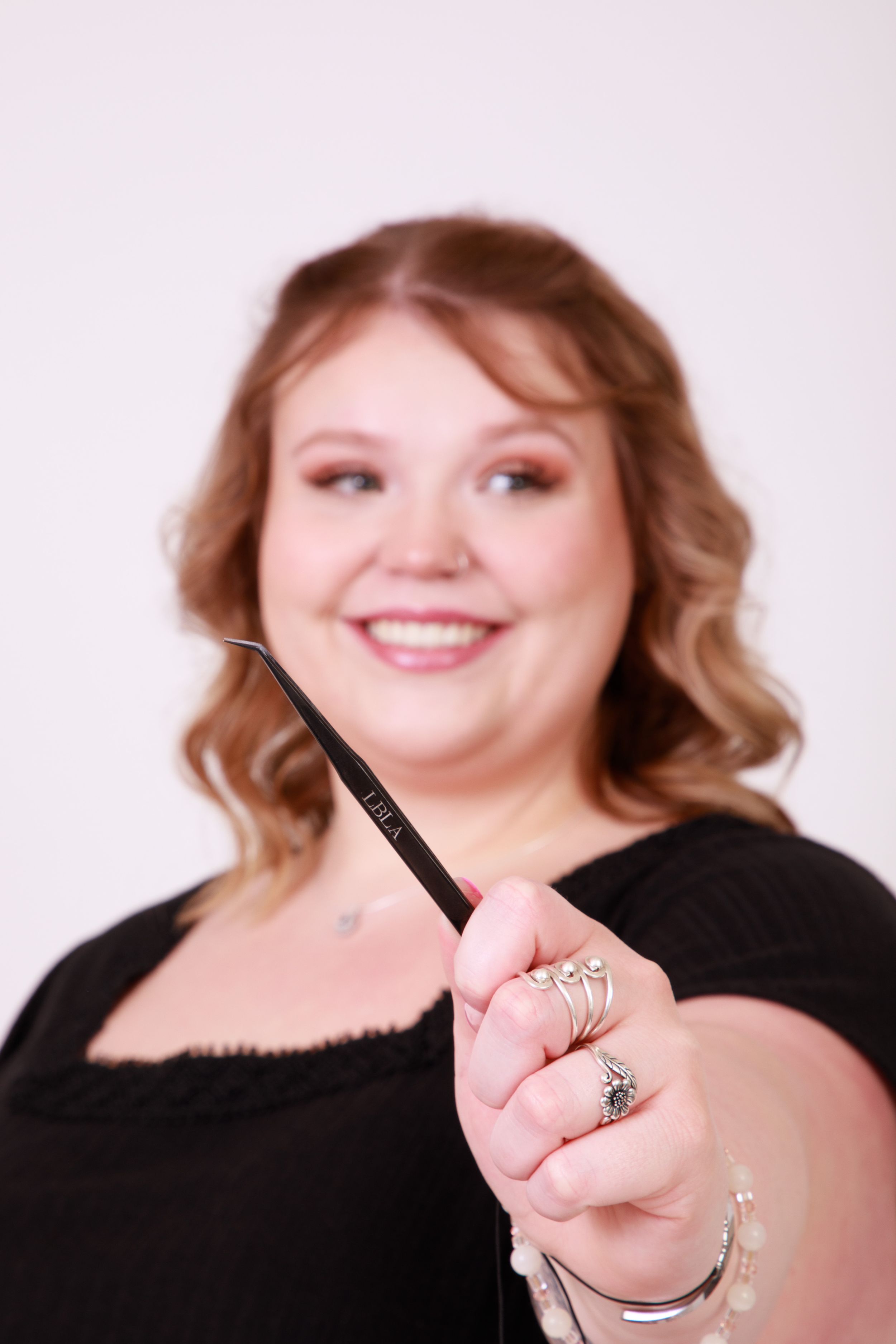 Portrait showing makeup brush with warm friendly smile against white backdrop.