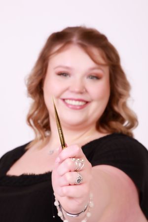 Close up portrait holding gold makeup brush with joyful expression.