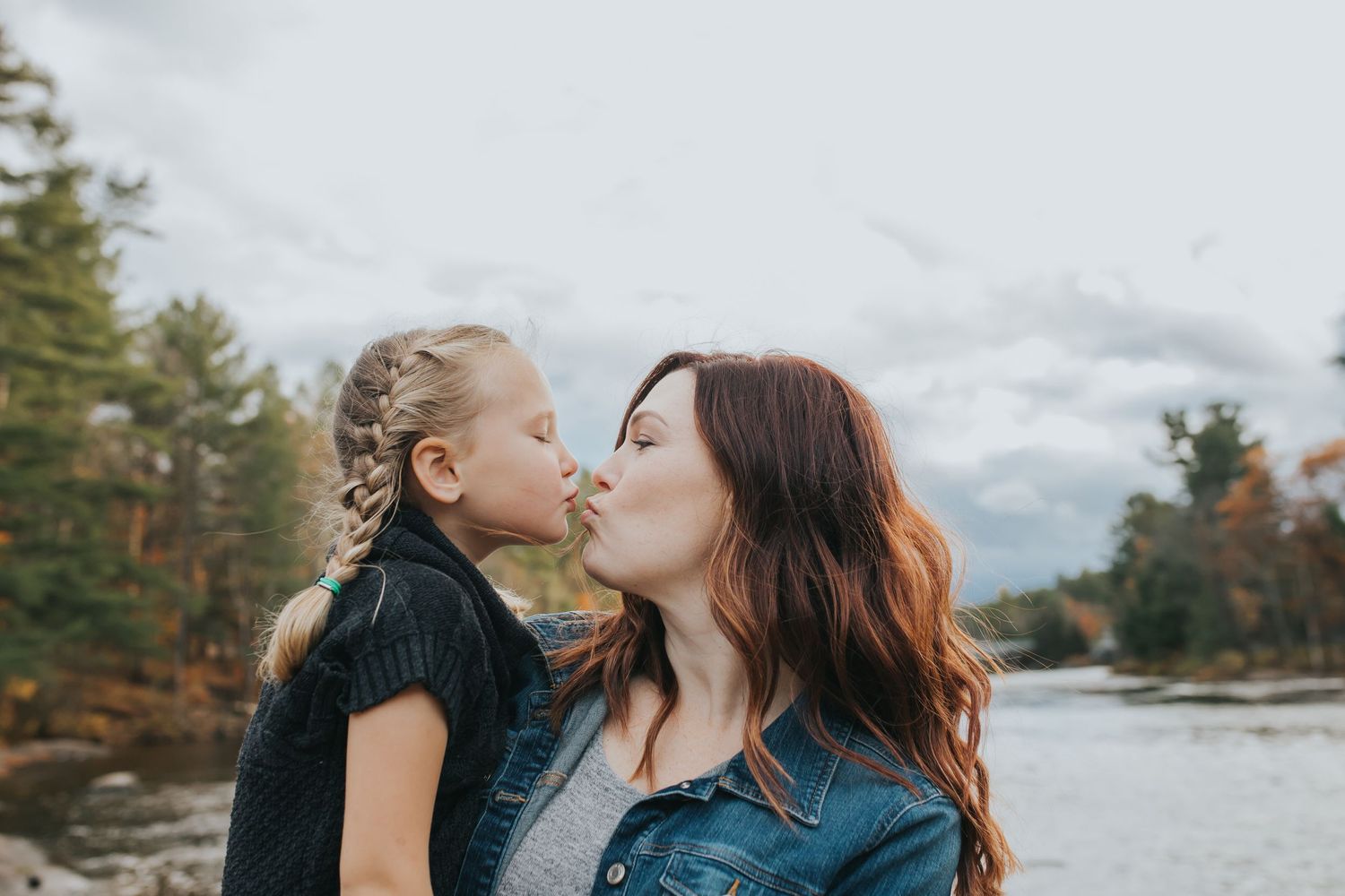 Portrait of young girl getting a kiss from her mom