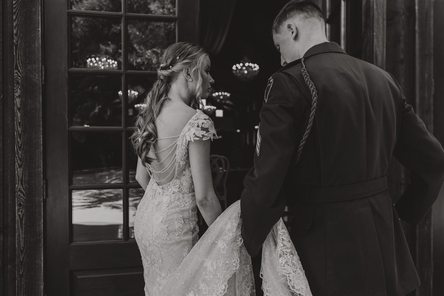 Black and white photo of couple entering through elegant doorway at formal event.