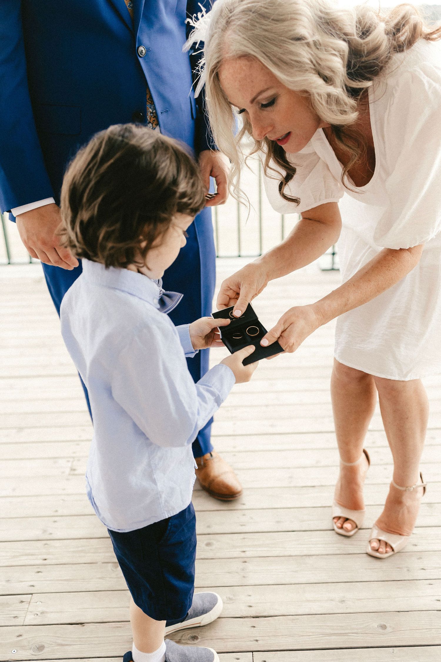 A young child in formal attire interacts with adults during a special occasion.