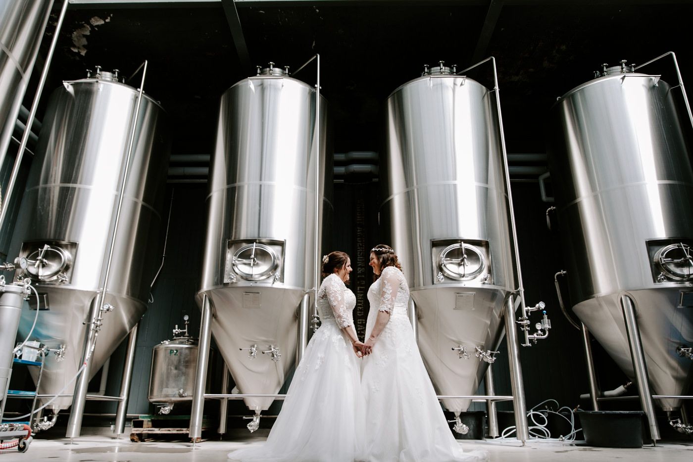 Wylam Brewery Wedding In Newcastle with 2 brides in front of brewing tanks