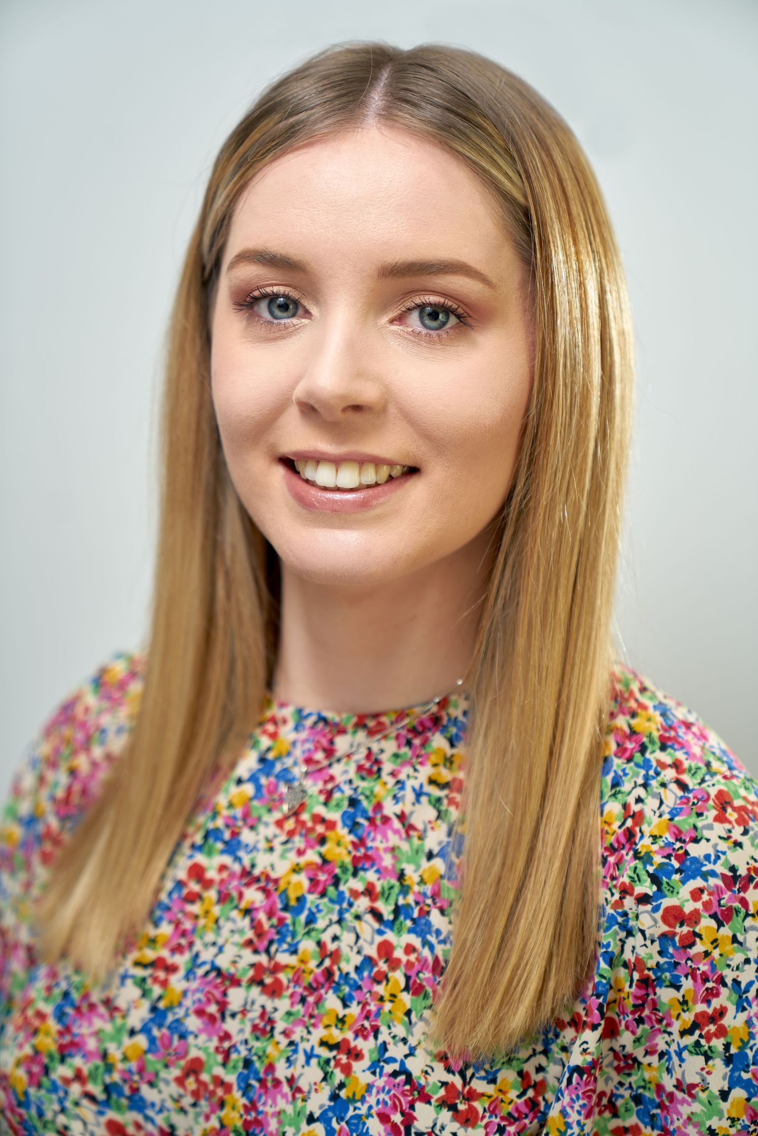 Corporate Headshot Professional Business Portrait of a Teacher wearing a floral patterned blouse on a grey background
