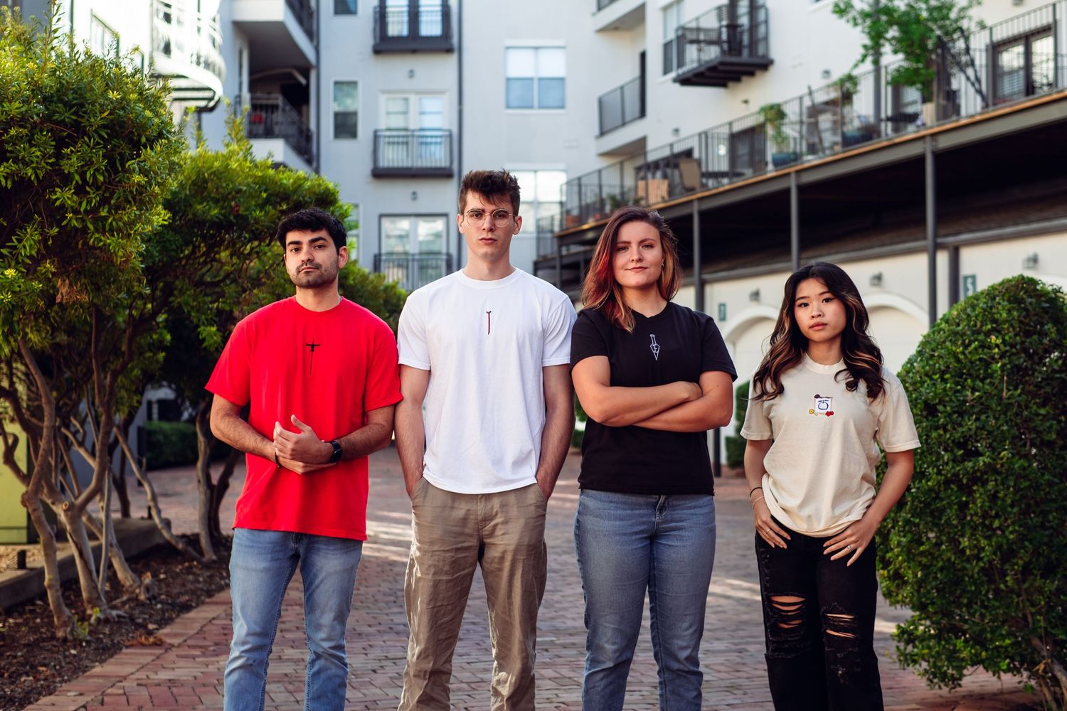 Group poses casually outside modern apartment building on sunny day.