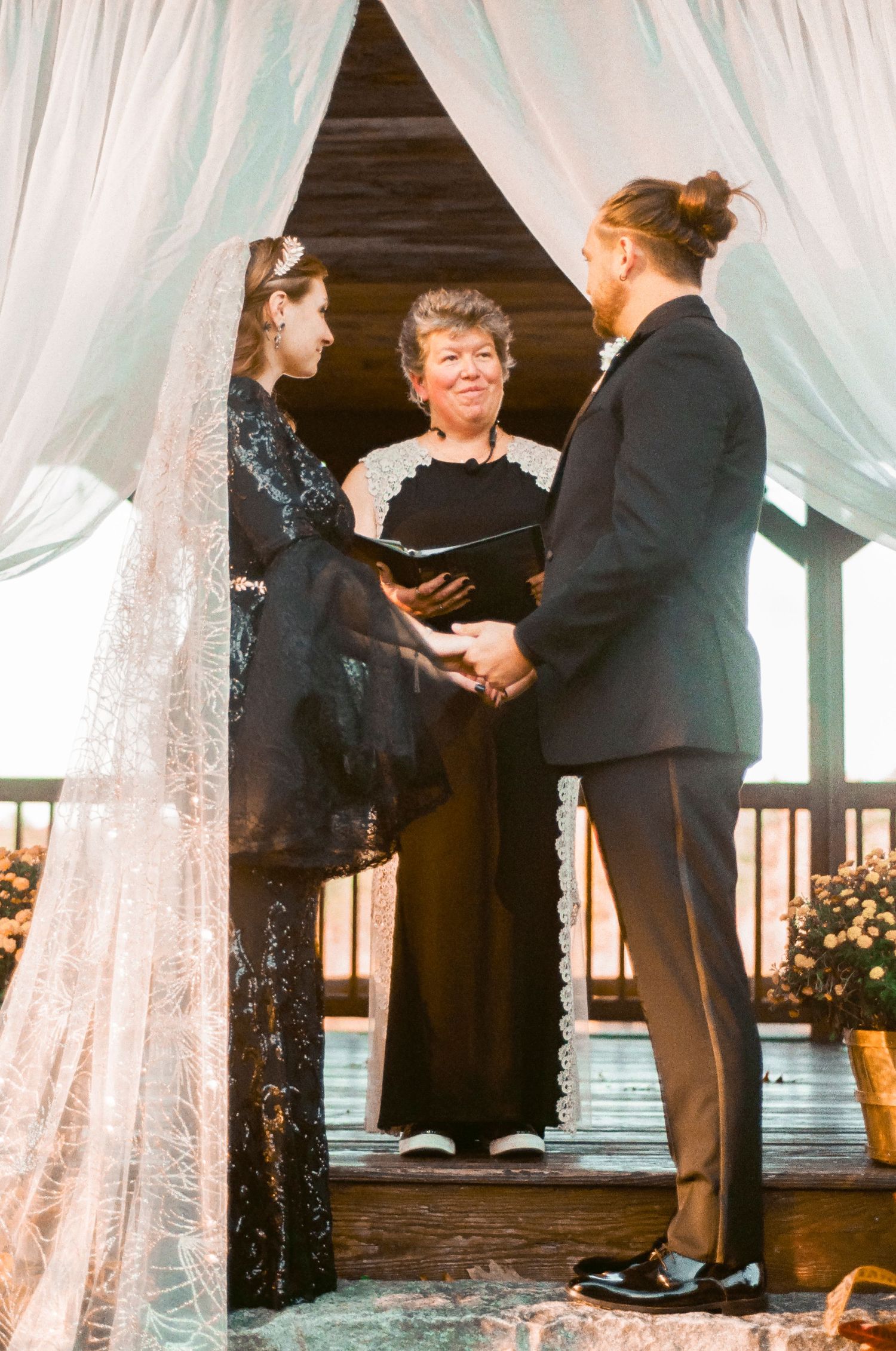 A ceremony taking place under a draped gazebo with the officiant and couple standing together.