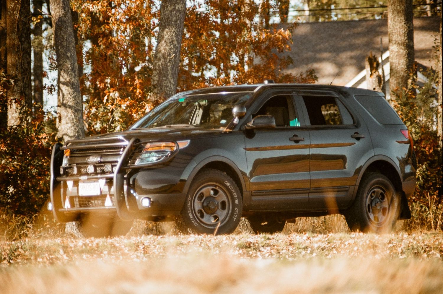 Black SUV with police equipment photographed in fallen autumn leaves.