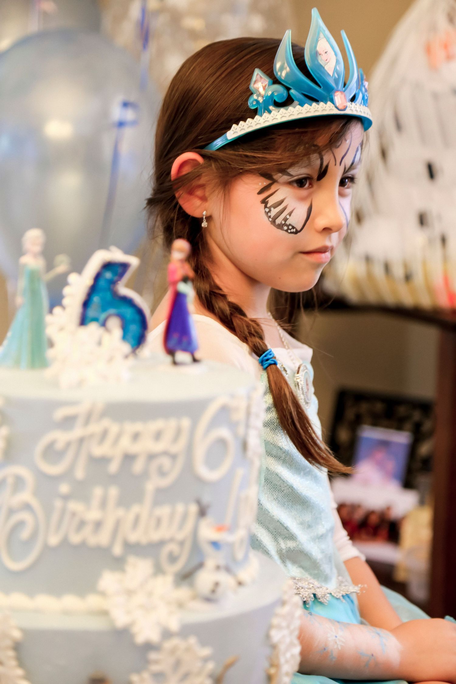 birthday party cake in the foreground and the birthday girl in the background