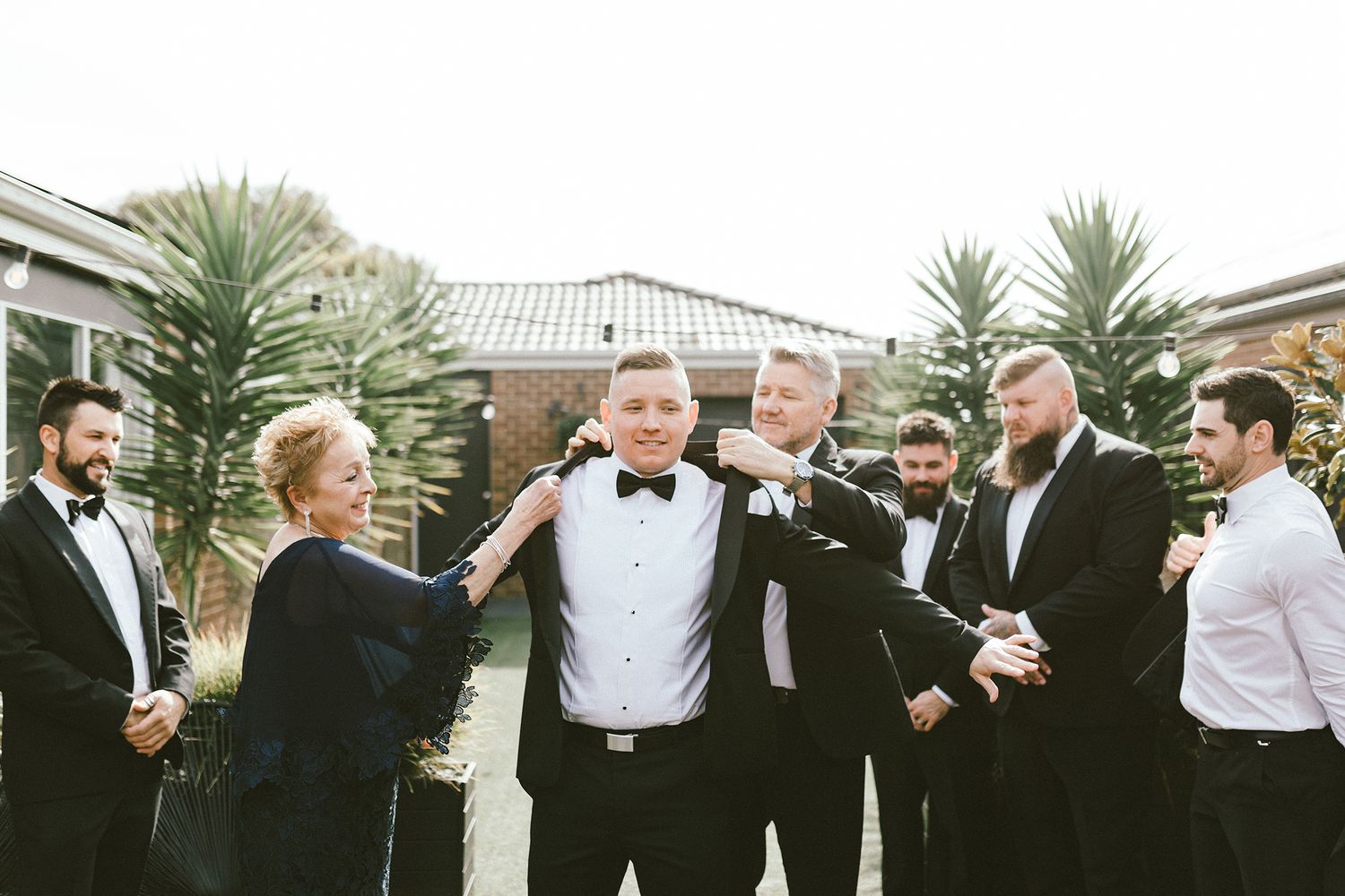 A group in formal attire sharing a moment during preparations outside.