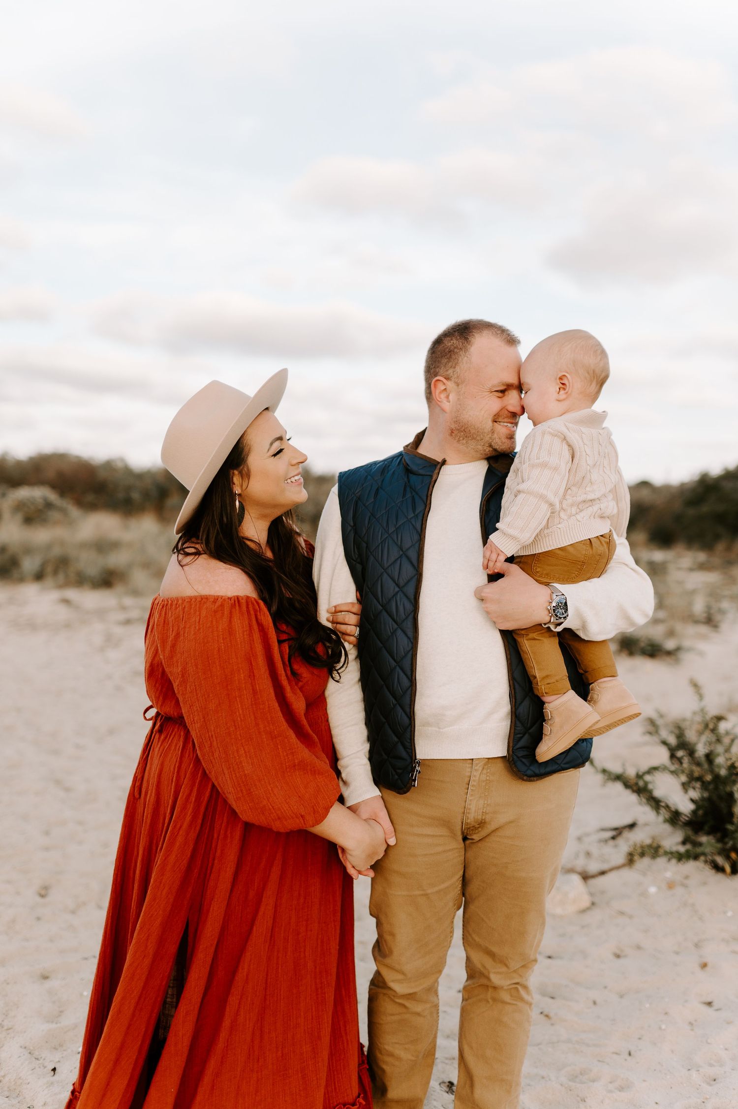 Family in desert landscape with woman in red dress during sunset.
