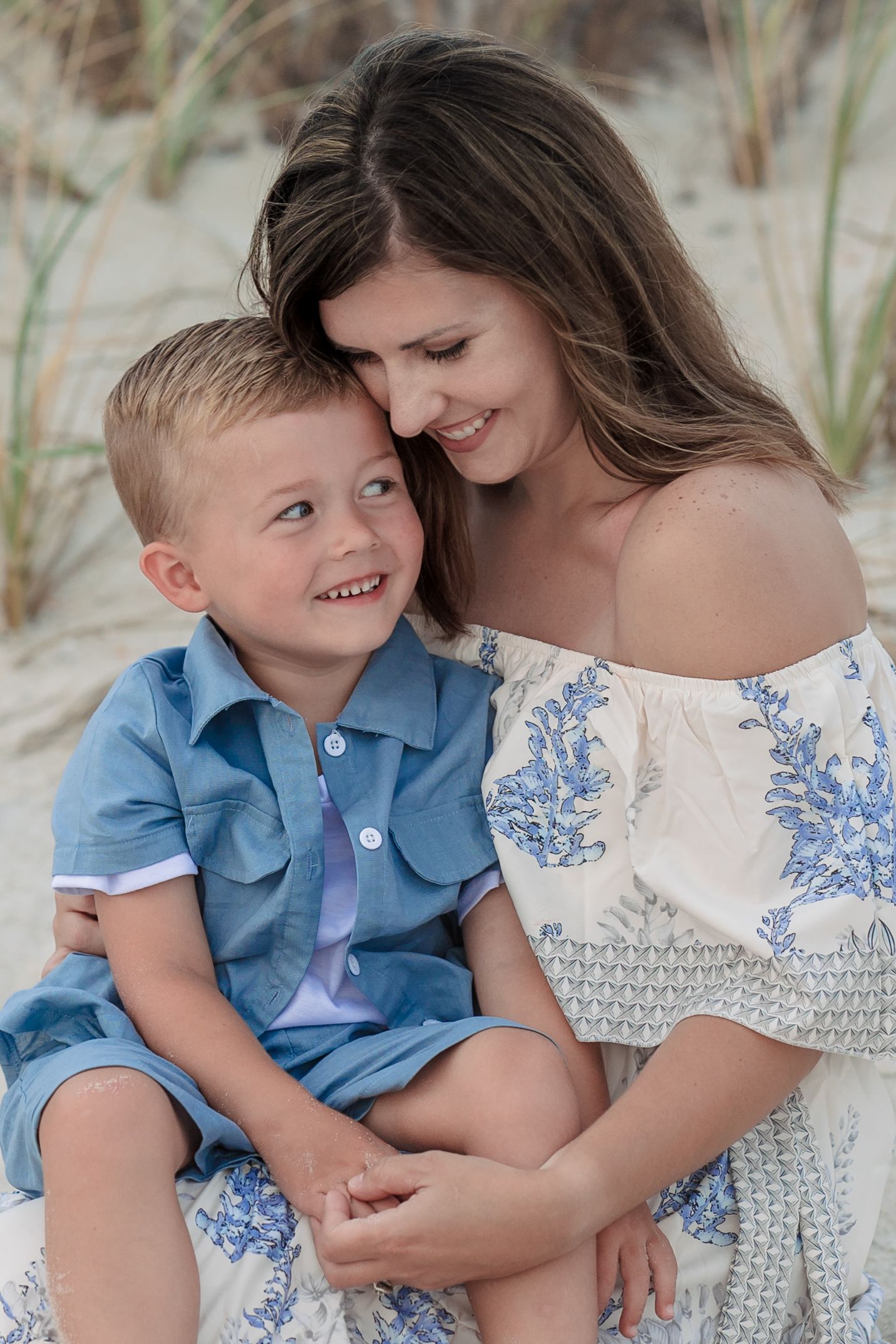 Sweet family beach portraits with coordinating blue and white outfits among sand dunes.
