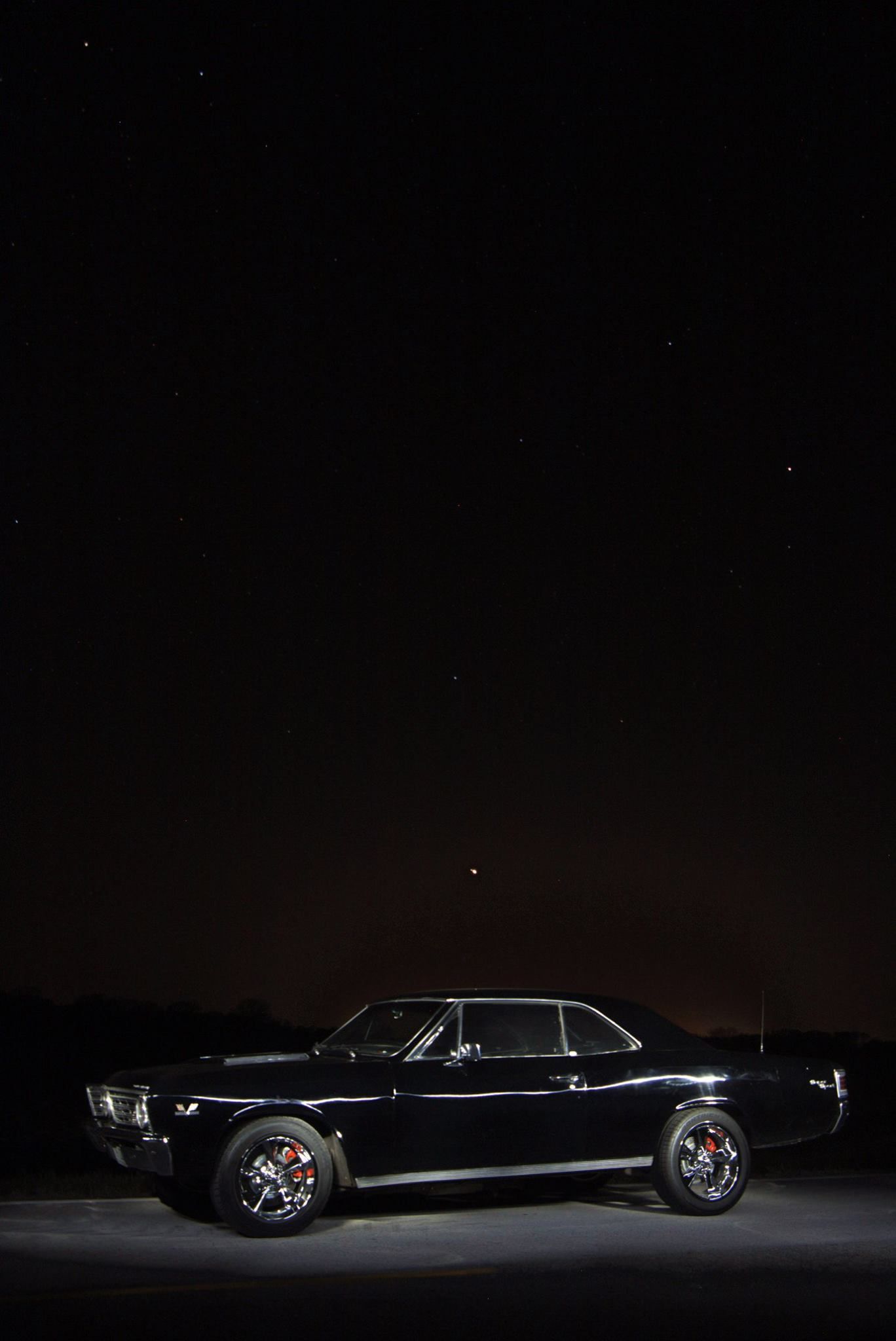 Classic black vintage car silhouette photographed in dramatic low-key lighting.