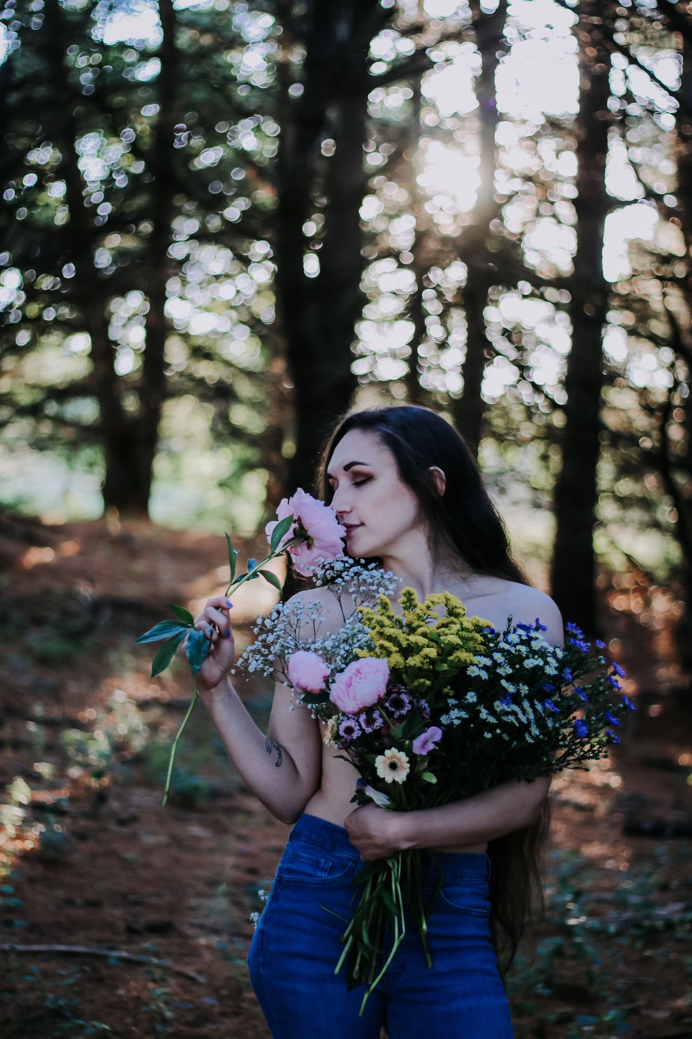 Romantic forest scene with flowers and sunlight filtering through trees.
