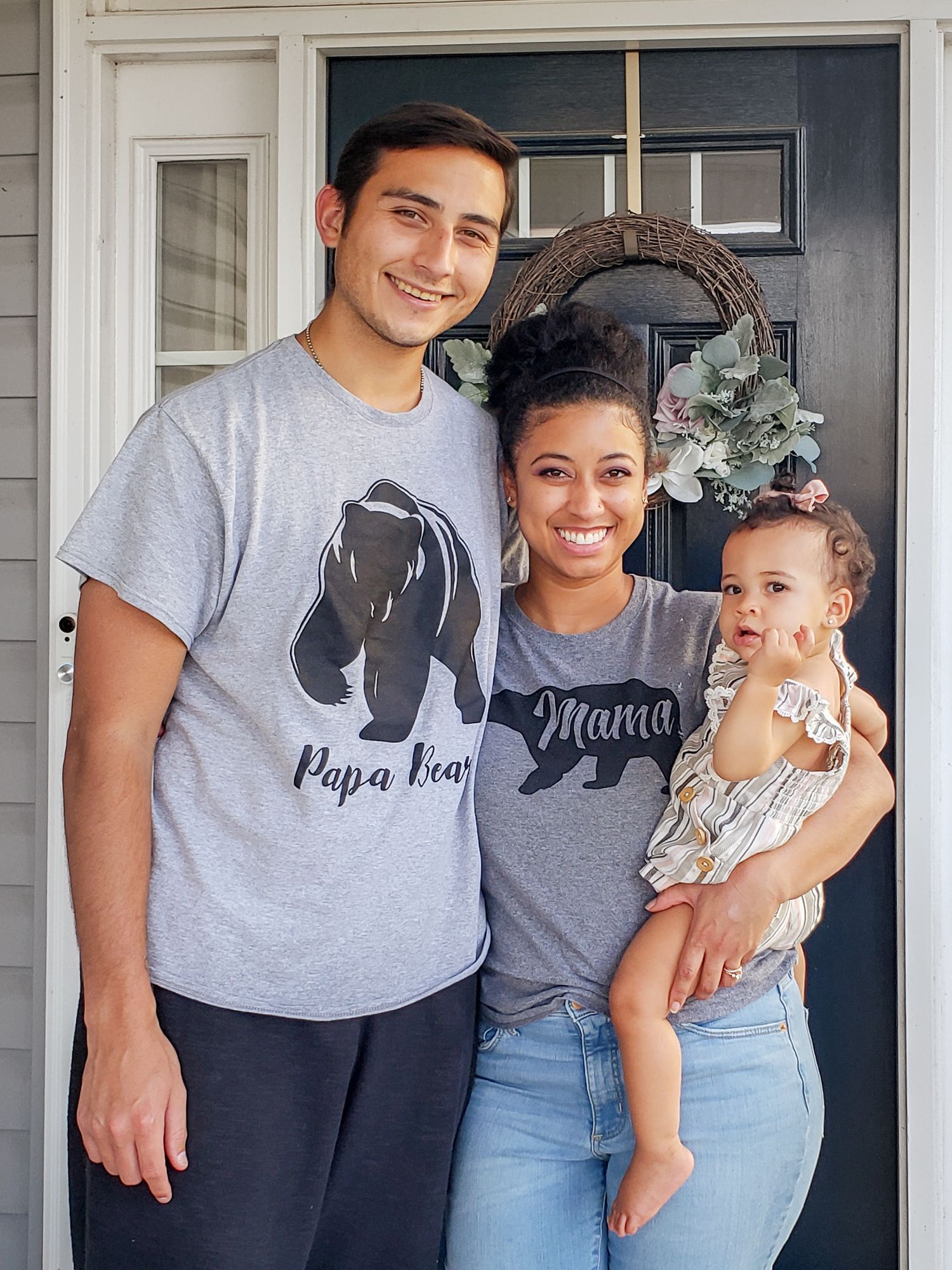 Family wearing matching bear themed t-shirts posing together outside their front door.