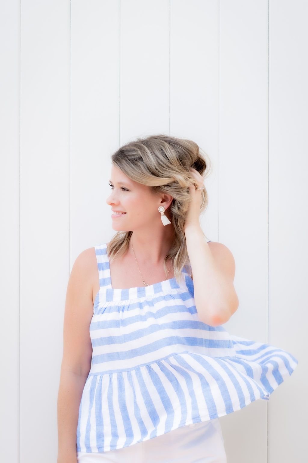 Light blue striped peplum top blowing in breeze against white background.
