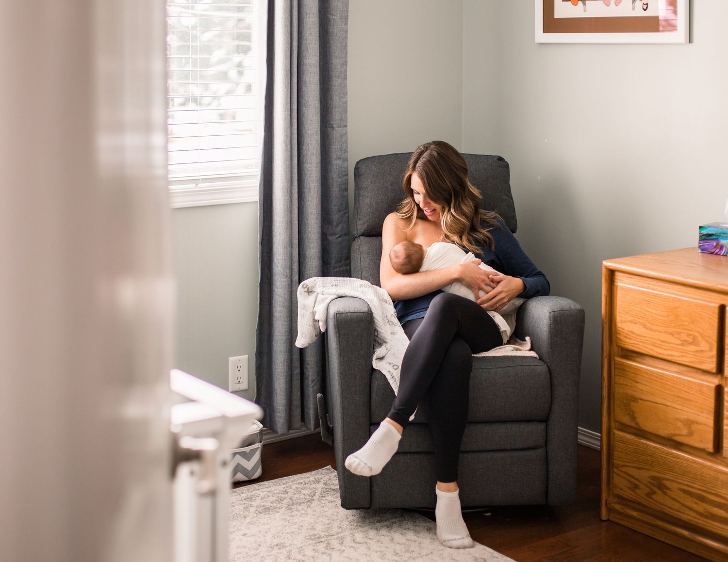 Mom holding newborn baby in rocking chair and breastfeeding with cozy quiet scene photo by Pelka Photography Alicante